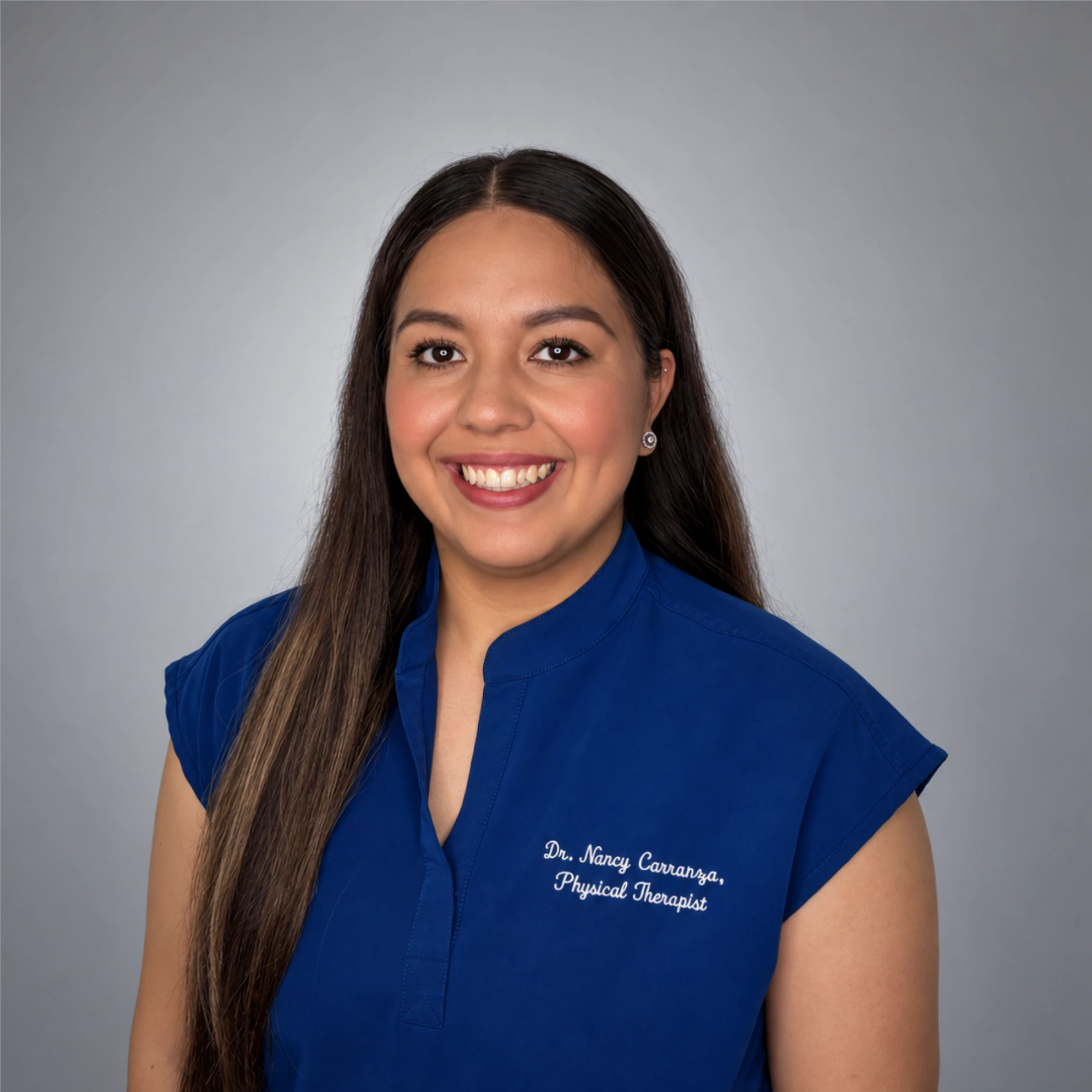 Dr. Nancy Carranza, PT, DPT, smiling in her blue Synergy Physical Therapy uniform